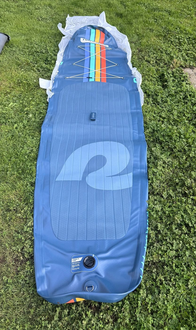 Weekender unrolled flat on a lawn before inflation with its protective wrap still under the nose