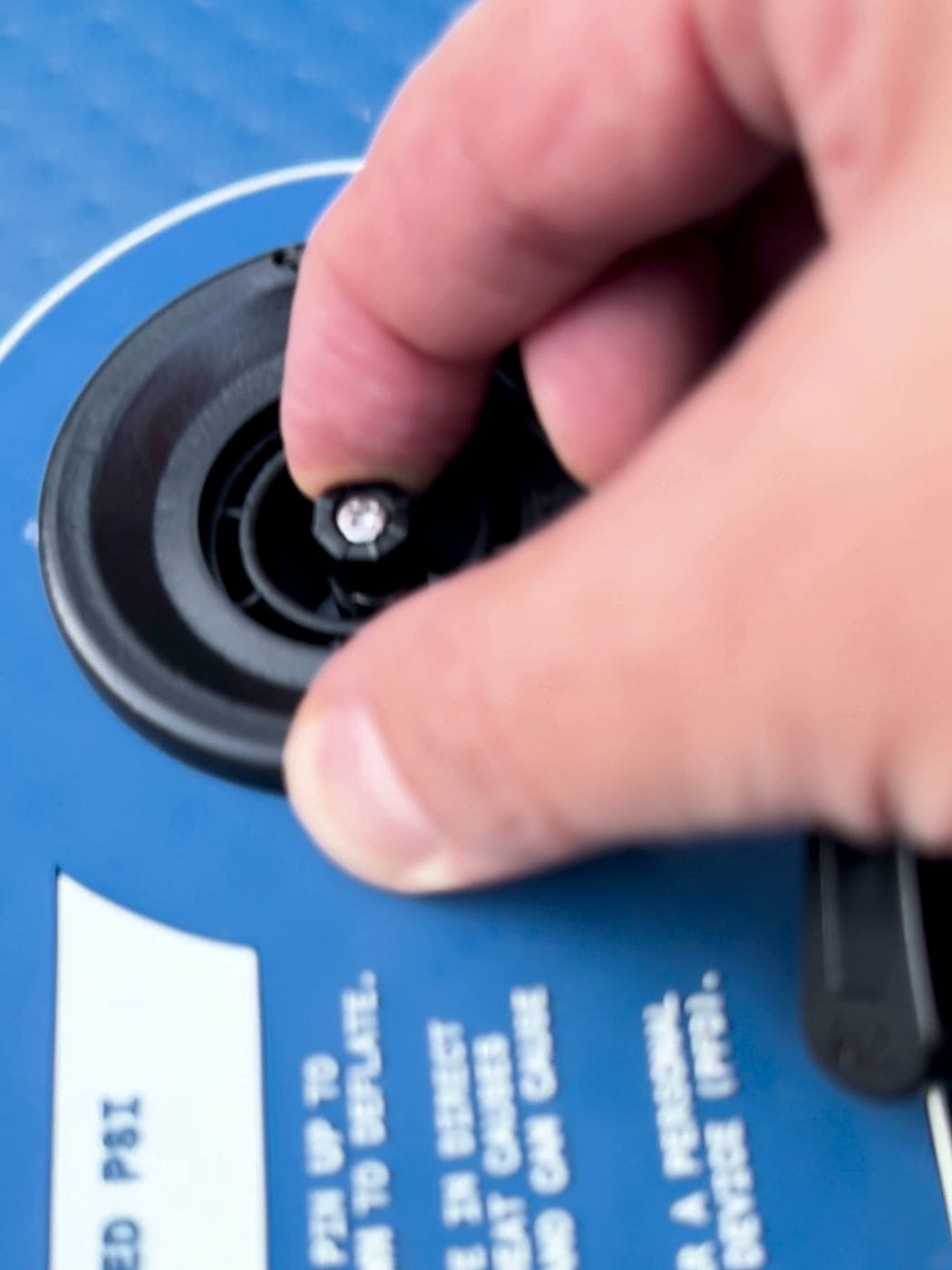 Finger pressing the valve pin down to deflate the Weekender beside the PSI label