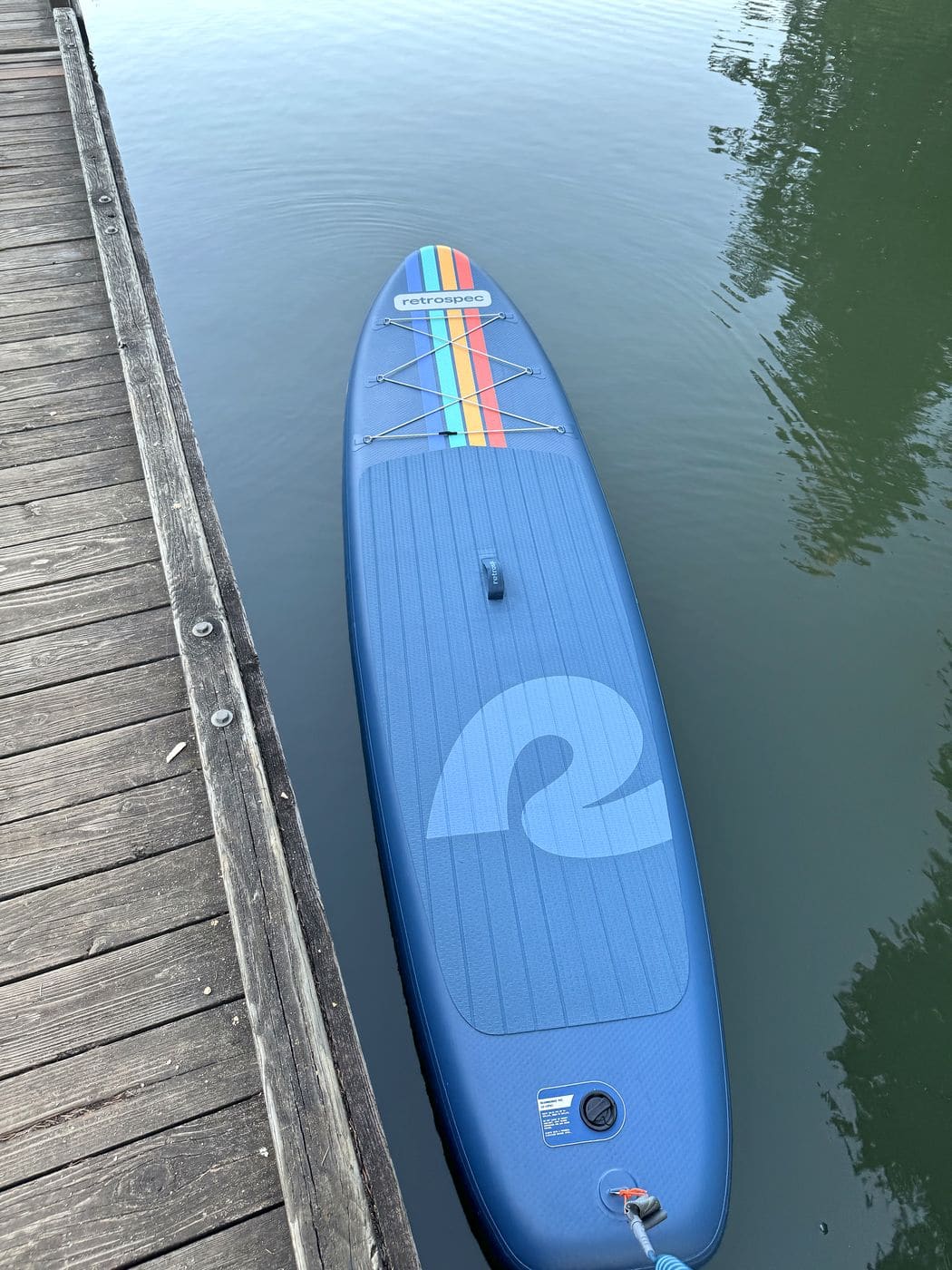 Top-down view of the Retrospec Weekender floating beside a wooden dock on green lake water