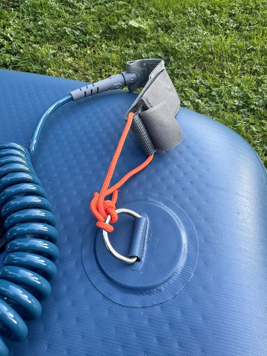 Orange leash cord cinched around the stainless tail D-ring of the Weekender beside the coiled leash