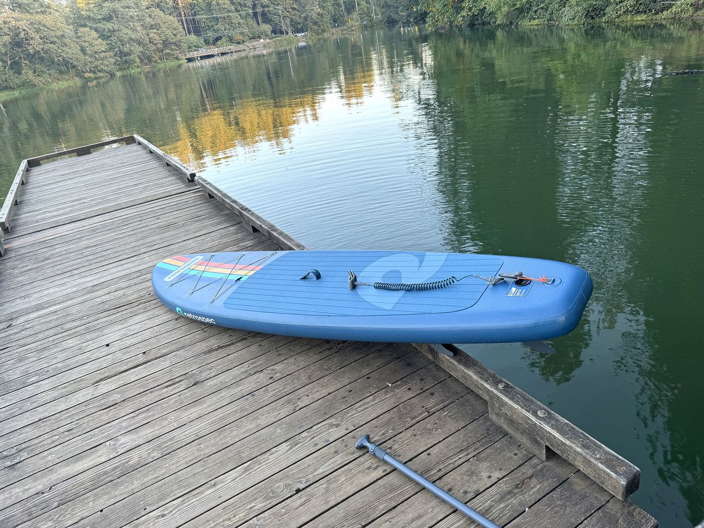 Weekender resting on the dock beside calm lake water reflecting evergreen trees